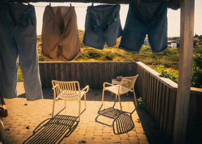 Clothes drying on a patio under bright sunlight, casting shadows on the ground.
