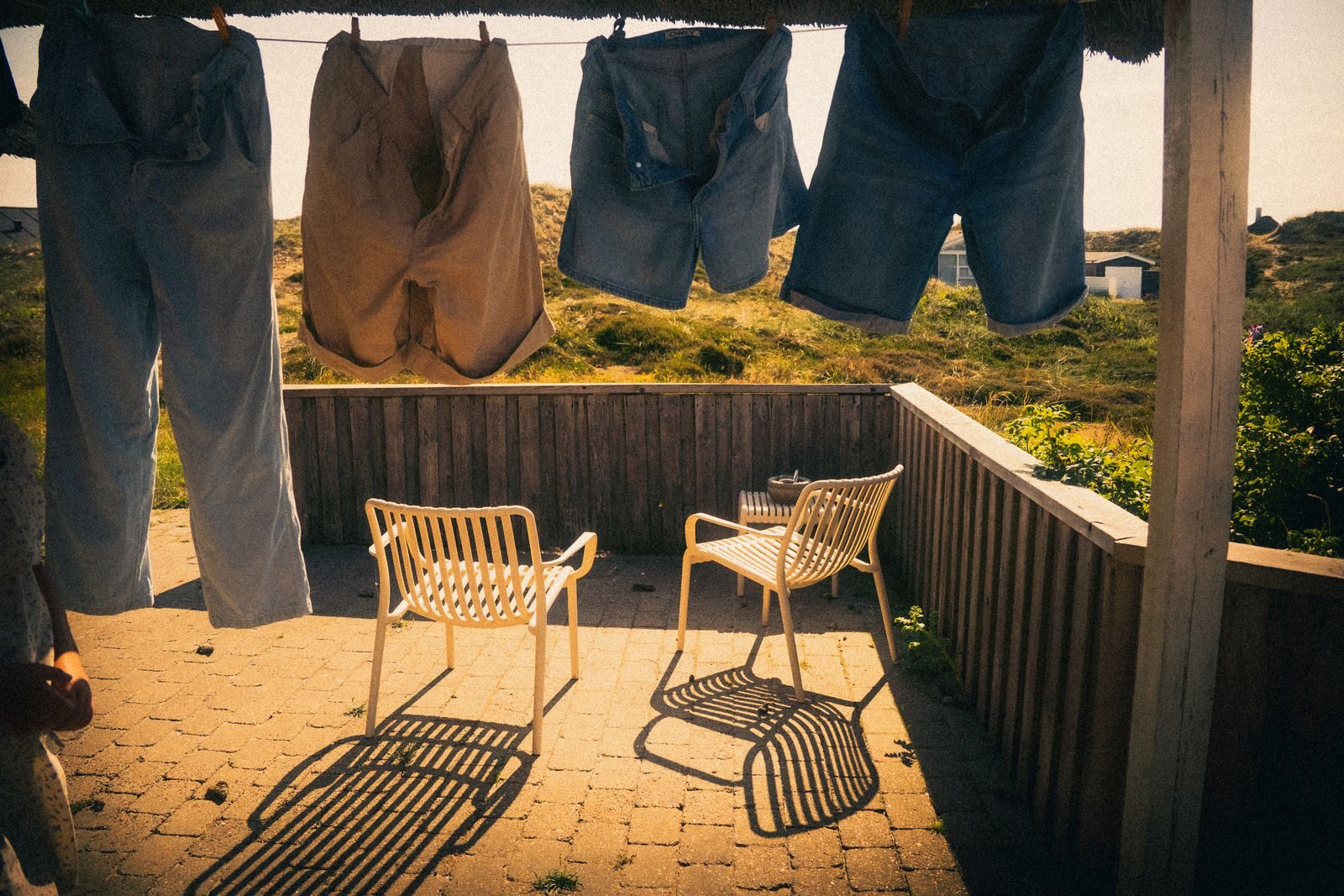 Clothes drying on a patio under bright sunlight, casting shadows on the ground.